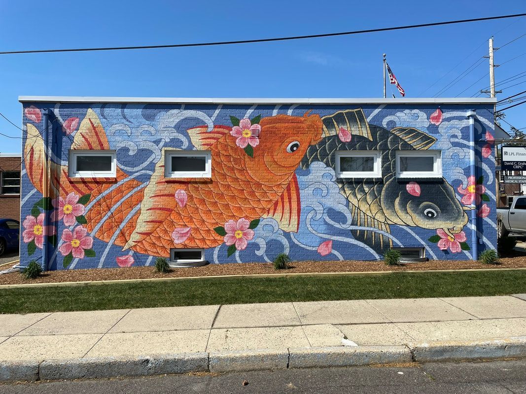 A small retail building with a vibrant mural of a yellow sun, black geometric patterns, and a purple paintbrush.