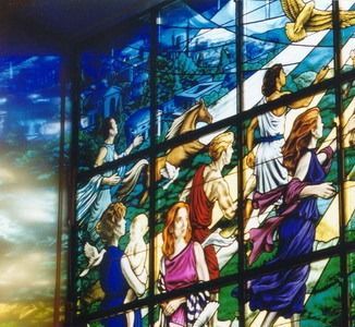 A statue of a mosaic head is sitting on a wooden stump.