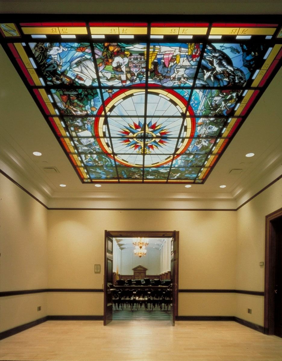 A storefront named Leap's with a large, colorful mural of a paint brush on its side wall next to a grassy lawn.