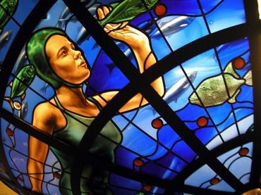 Stained-glass artwork of a person reaching upward among blue and red abstract shapes