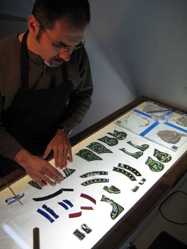 A person carrying a baby in a carrier and a child stand in front of a colorful wall mural featuring a large rooster.