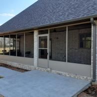 Brick house porch with screened windows, white trim, and a concrete patio.