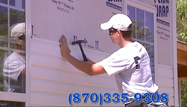 Worker writing on a large signboard outdoors with a phone number displayed at the bottom.