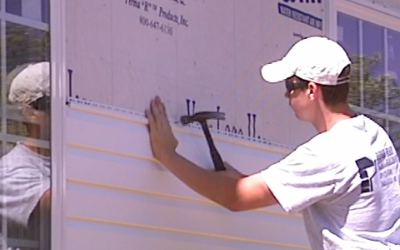 Man in white cap measures a storefront window with a level and tape measure