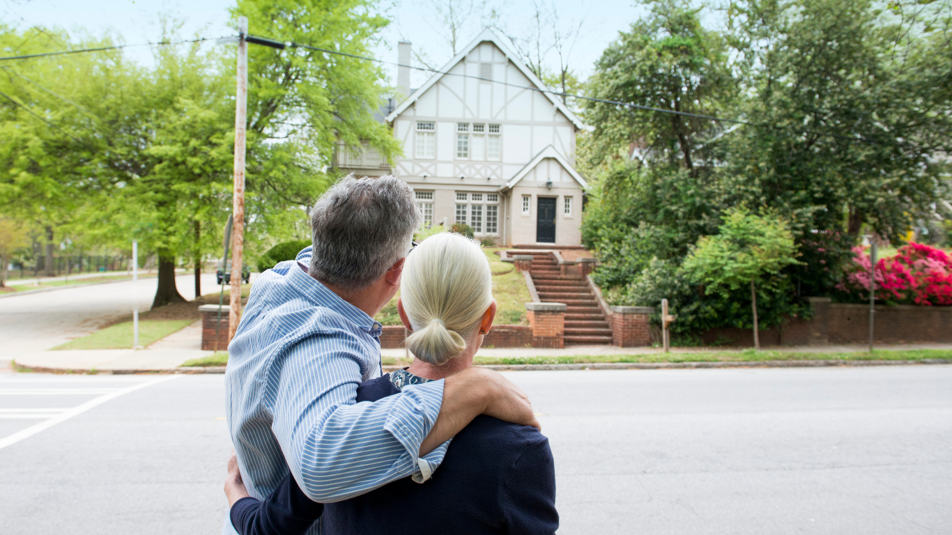 a man and a woman are standing in front of a house .