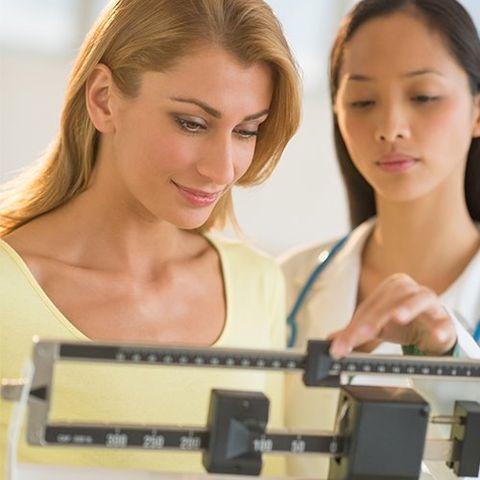 Doctor Weighing Woman on Balance Weight Scale — Hampton, VA — Doctors Weight Loss Clinic