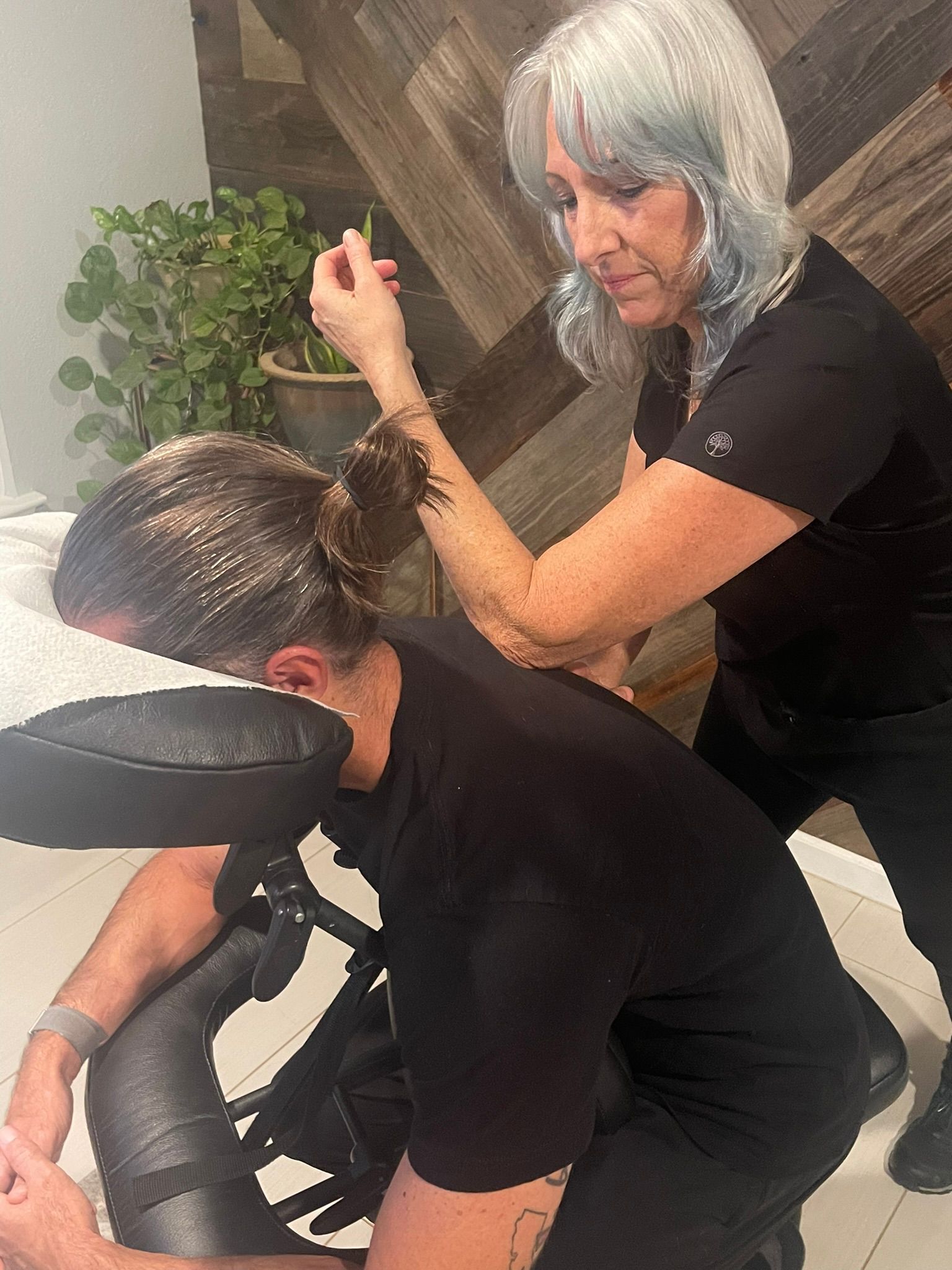 A woman is giving a man a massage in a chair.