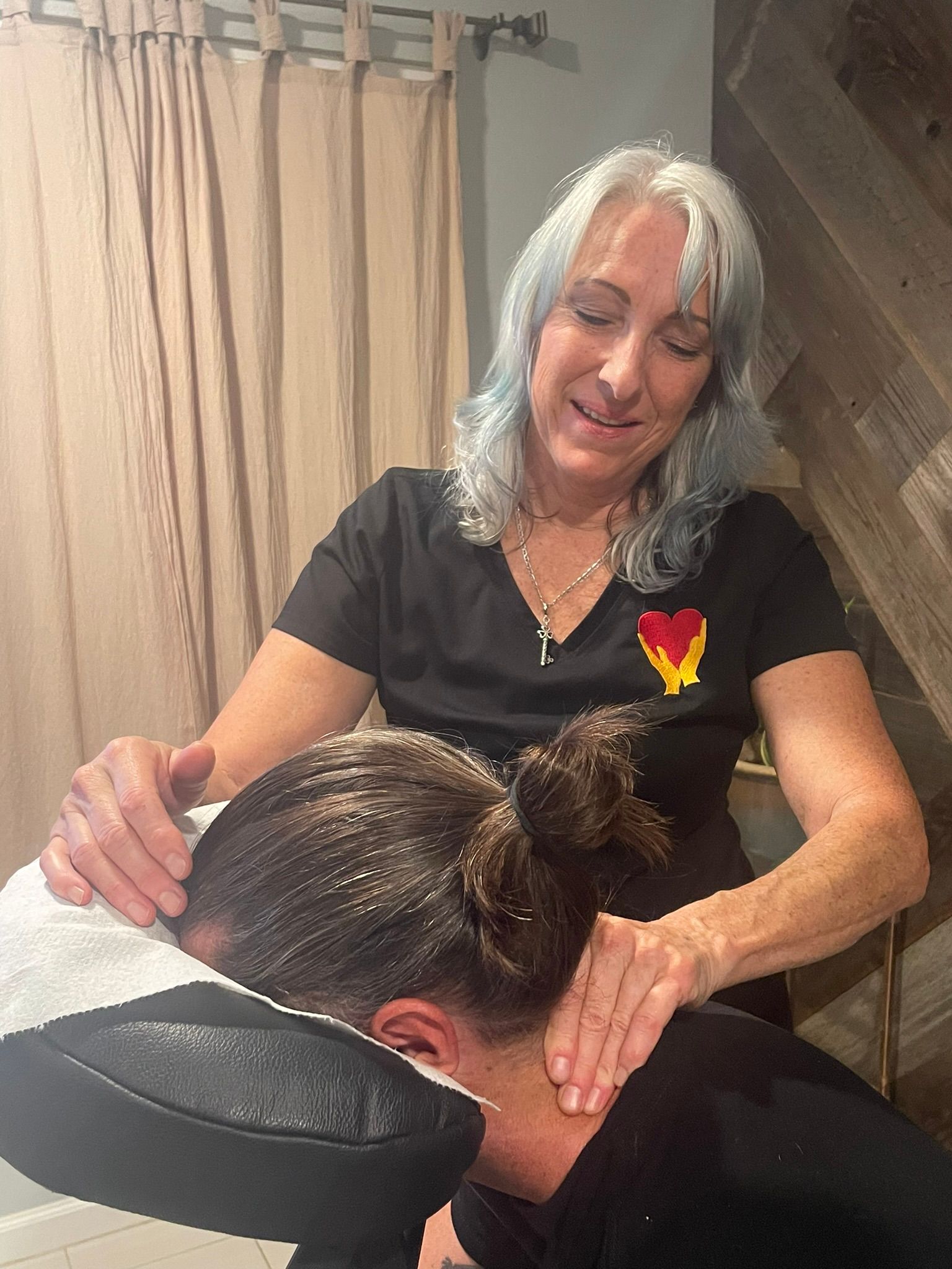 A woman is giving a massage to a woman in a chair.