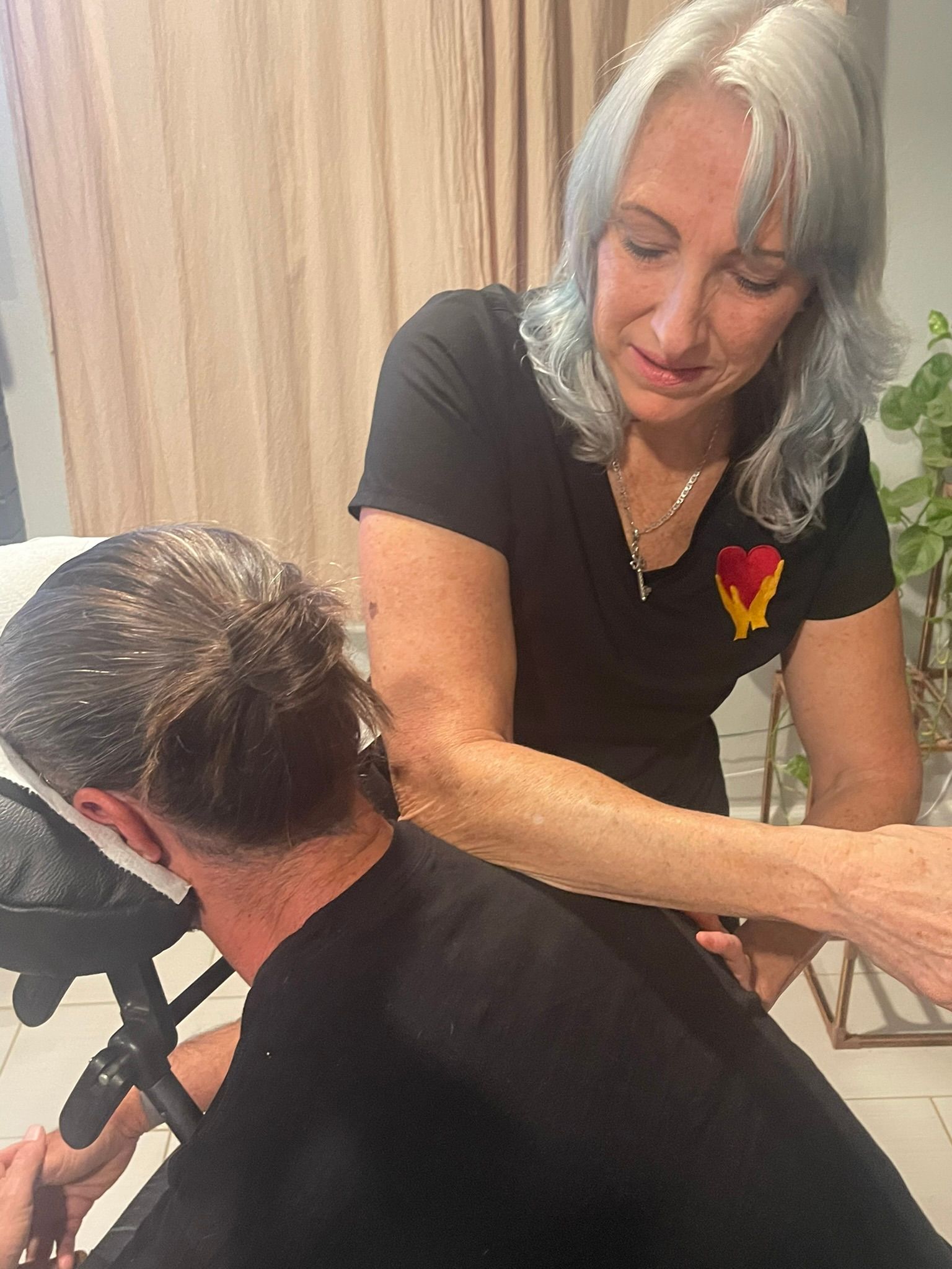 A woman is giving a man a massage in a chair.