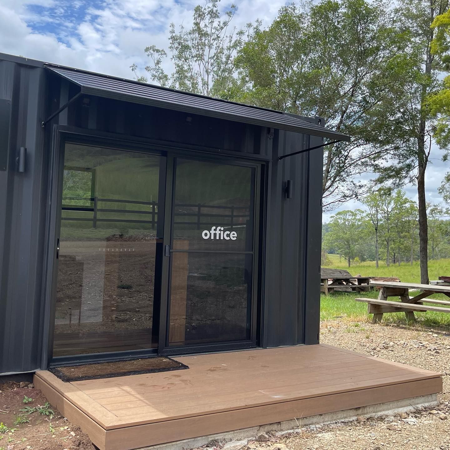 Black Office Container With Glass Doors and a Wooden Porch