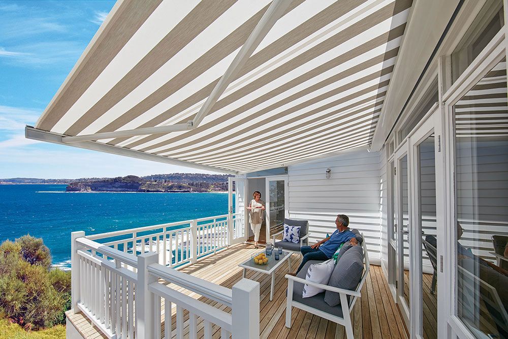 Folding Arm Awning Stripped Patio Area with People Around — Blinds in Bogangar, NSW