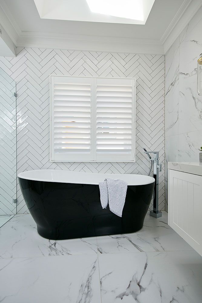 bath tub near window with shutters