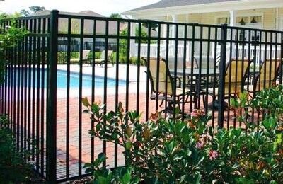 Black metal fence around a pool area with a table and chairs visible.
