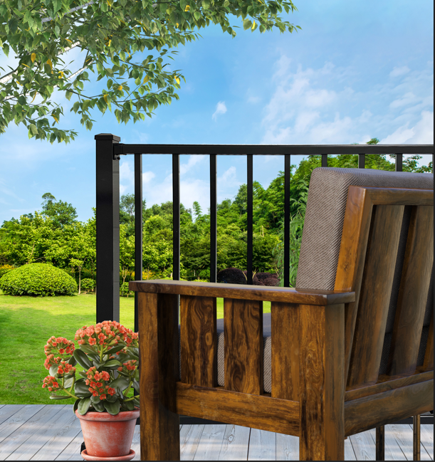 Wooden chair on a deck overlooking a green yard and trees, with a potted plant and black railing.