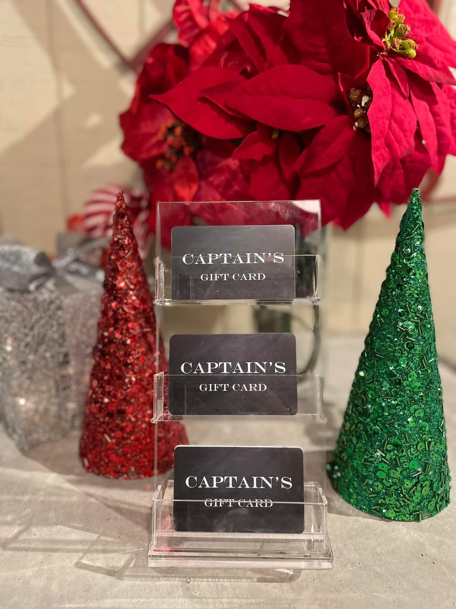 Clear display with Captain's gift cards, poinsettia, and glittery Christmas trees.