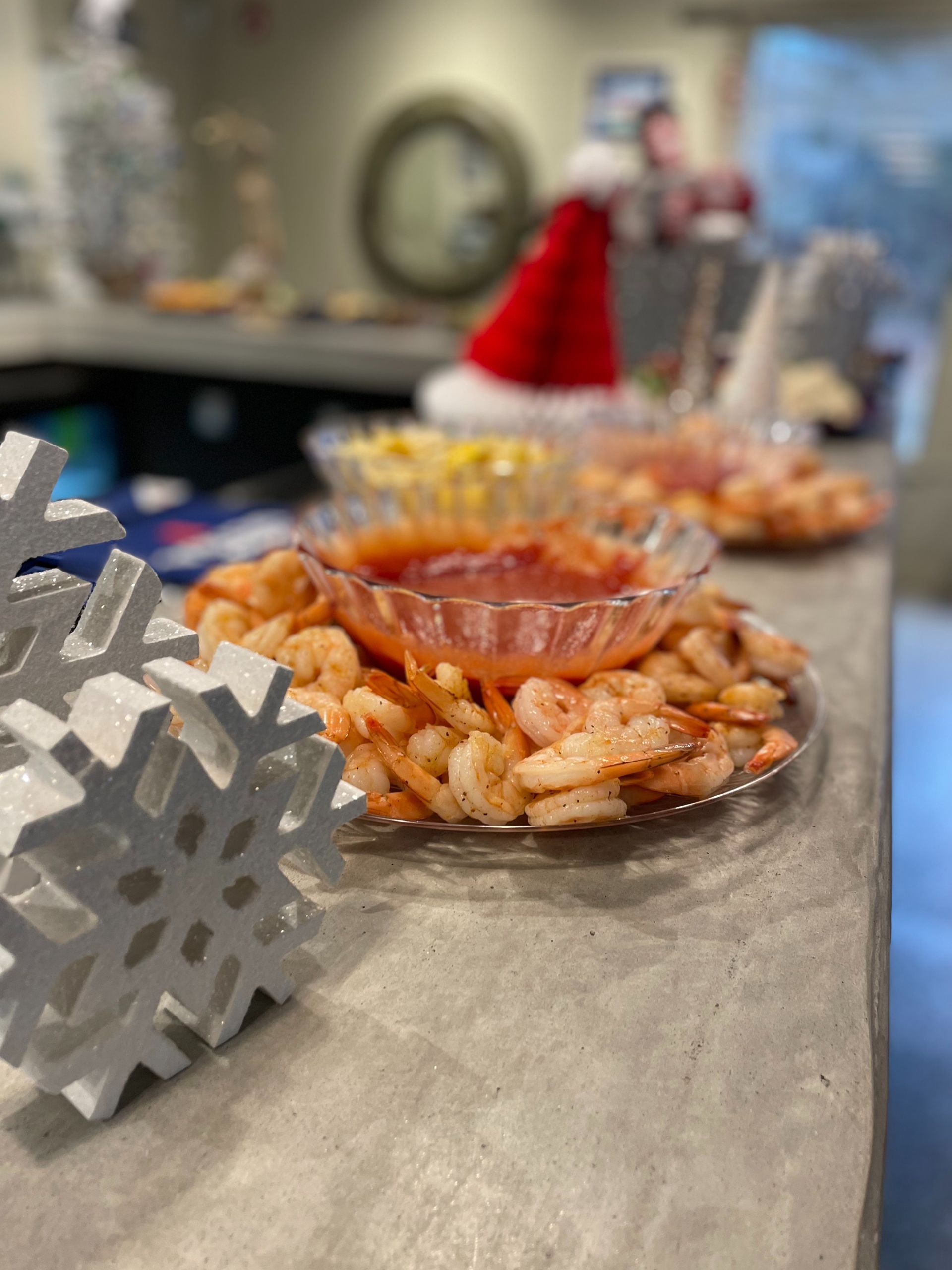 Shrimp cocktail platter on a countertop, with a Santa hat in the blurred background.