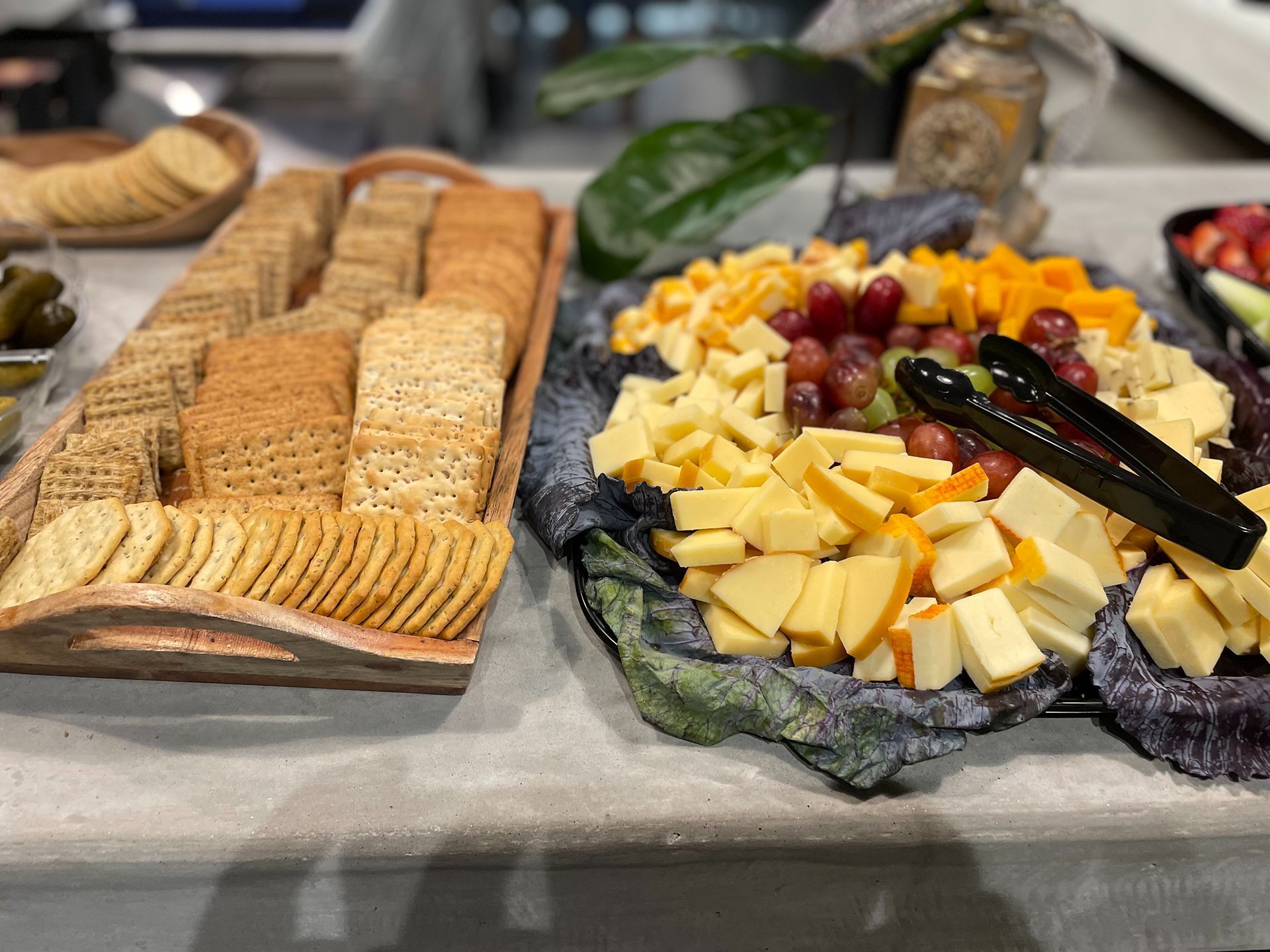 Charcuterie board with crackers, cheeses, and grapes.