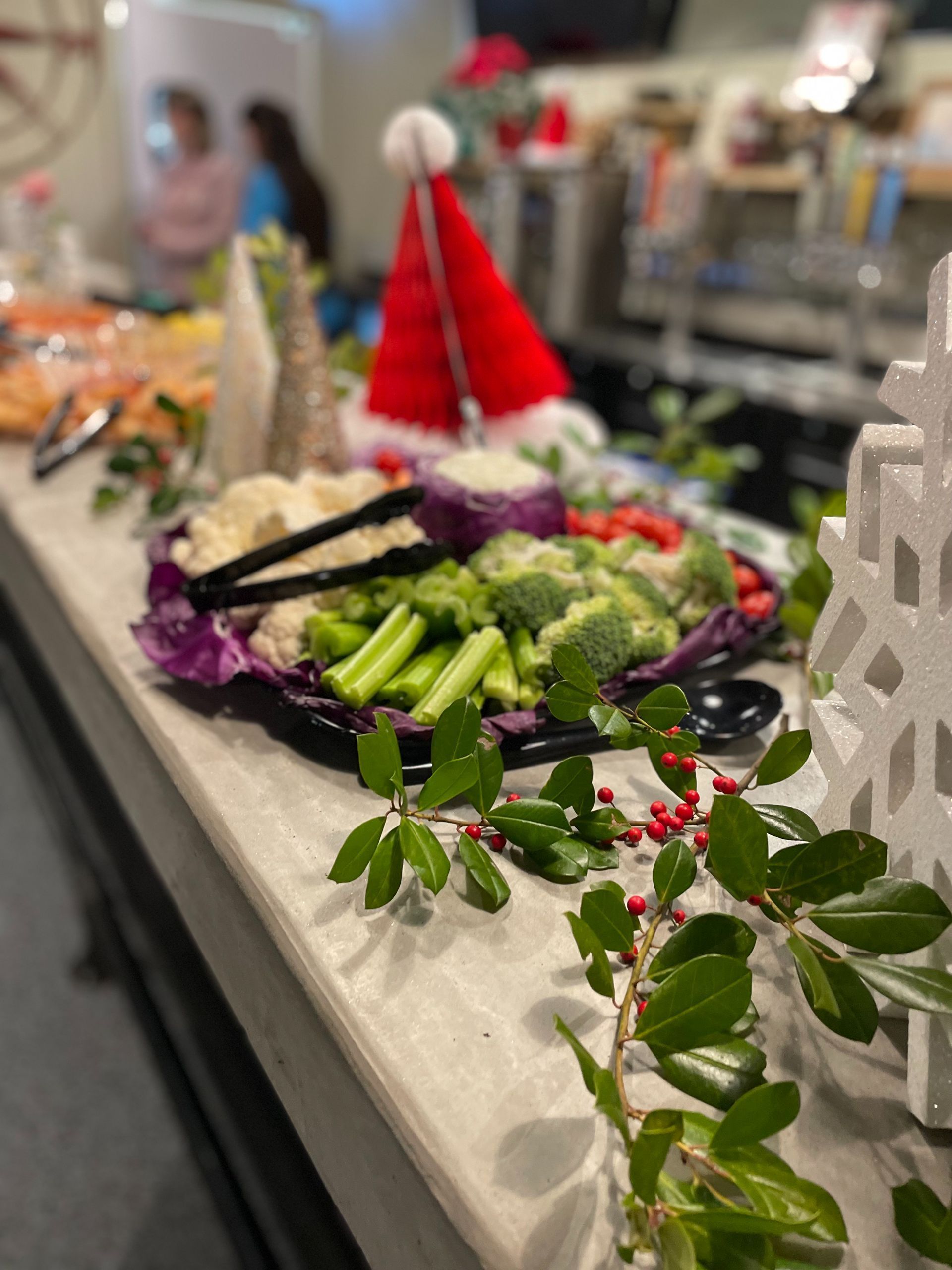 Vegetable platter with broccoli, cauliflower, and carrots; holiday decorations like Santa hat and garland.