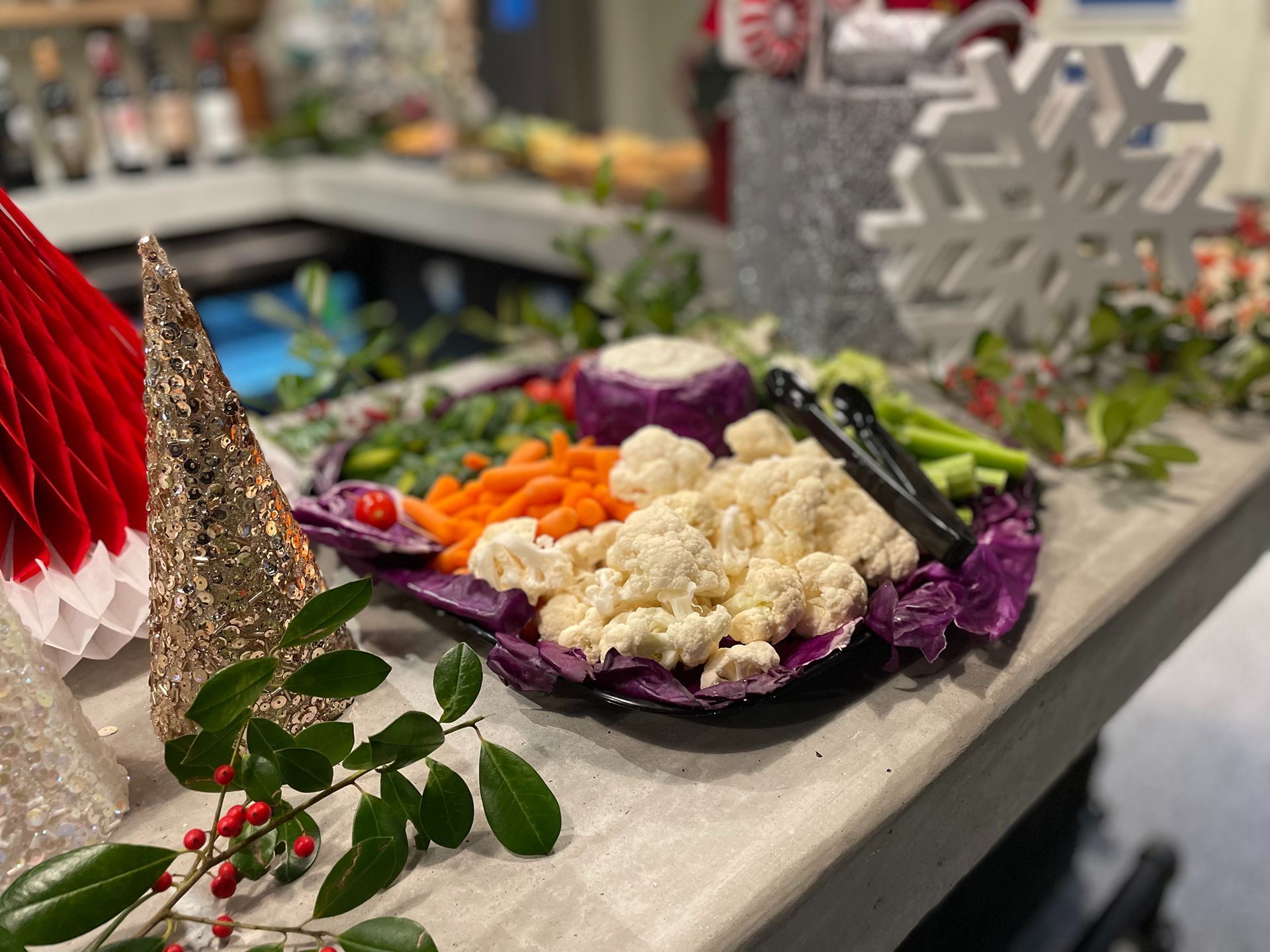 Vegetable platter with carrots, cauliflower, and celery on a decorated Christmas-themed table.