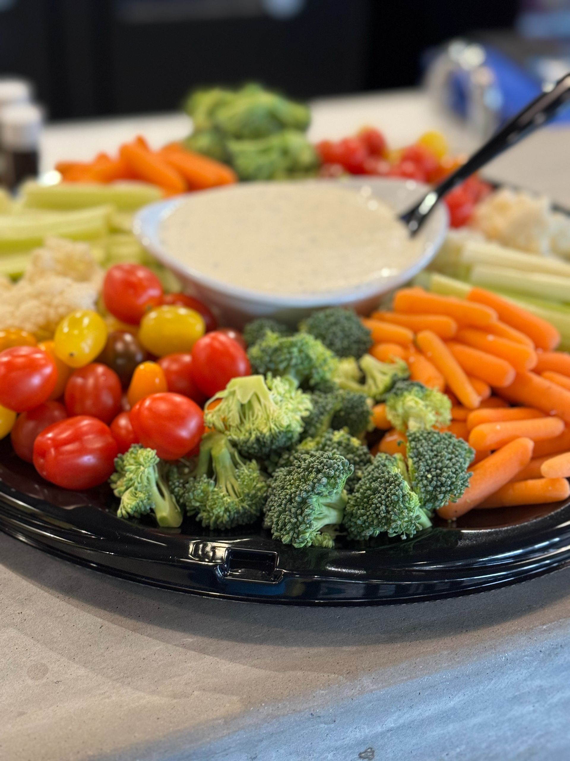 Vegetable platter with assorted raw vegetables, dip in the center.