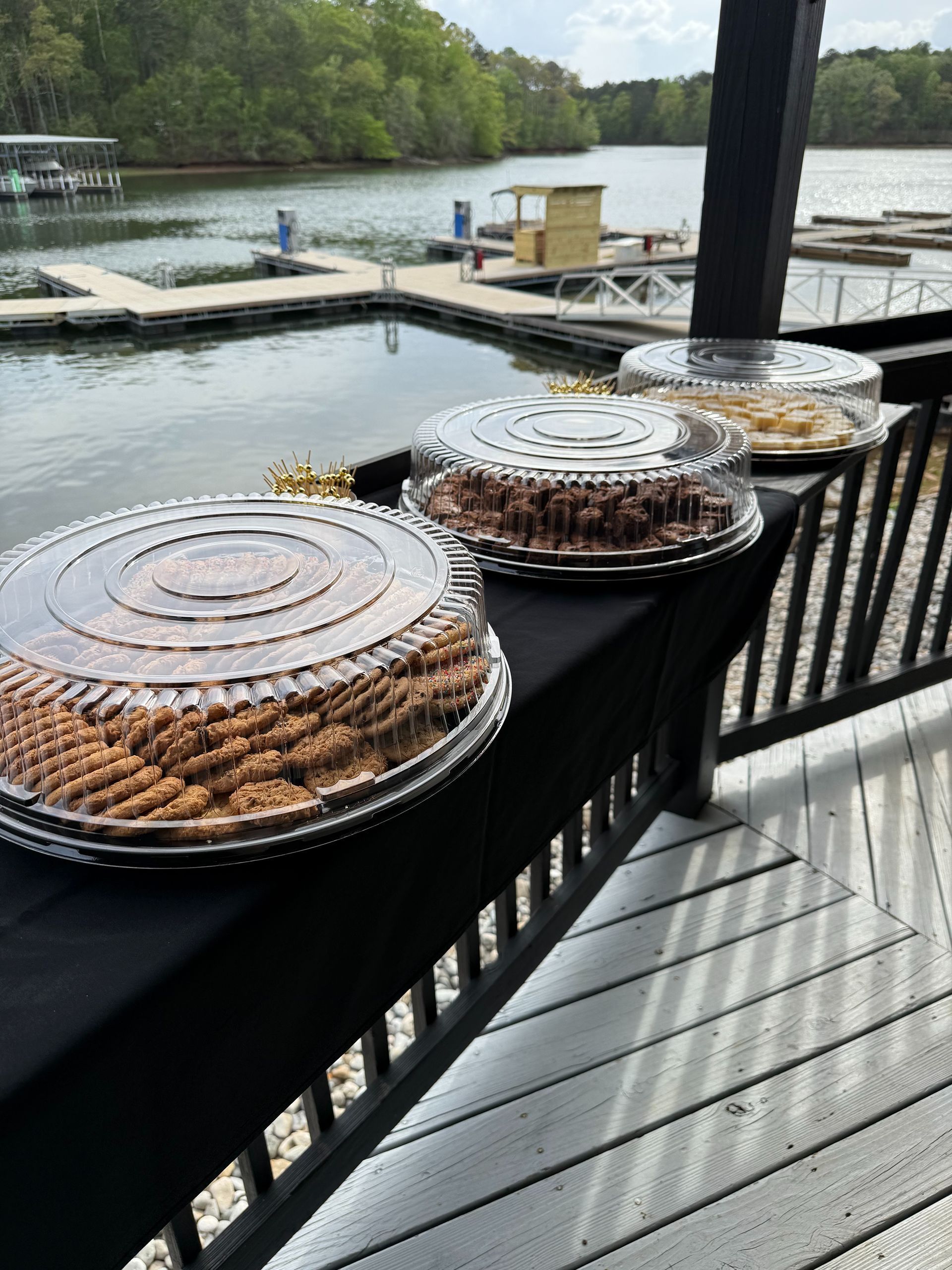 Trays of baked goods on a railing overlooking a lake with a dock.