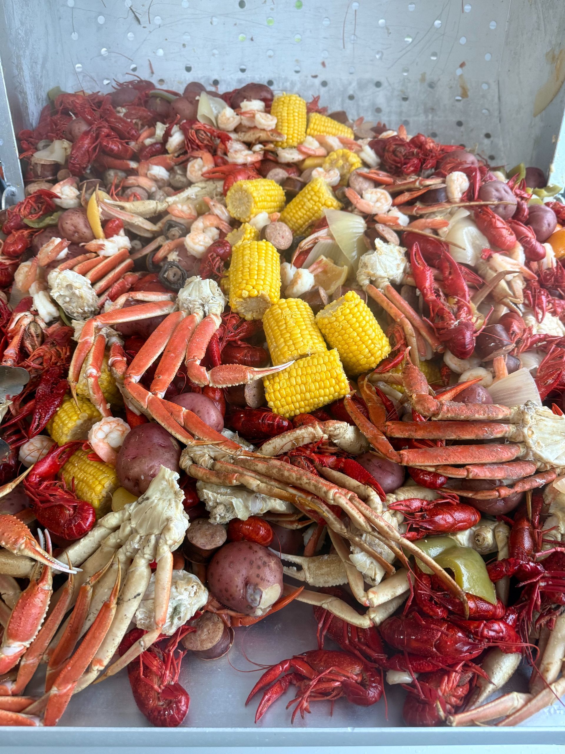 A seafood boil with red crawfish, crab, corn, and potatoes.