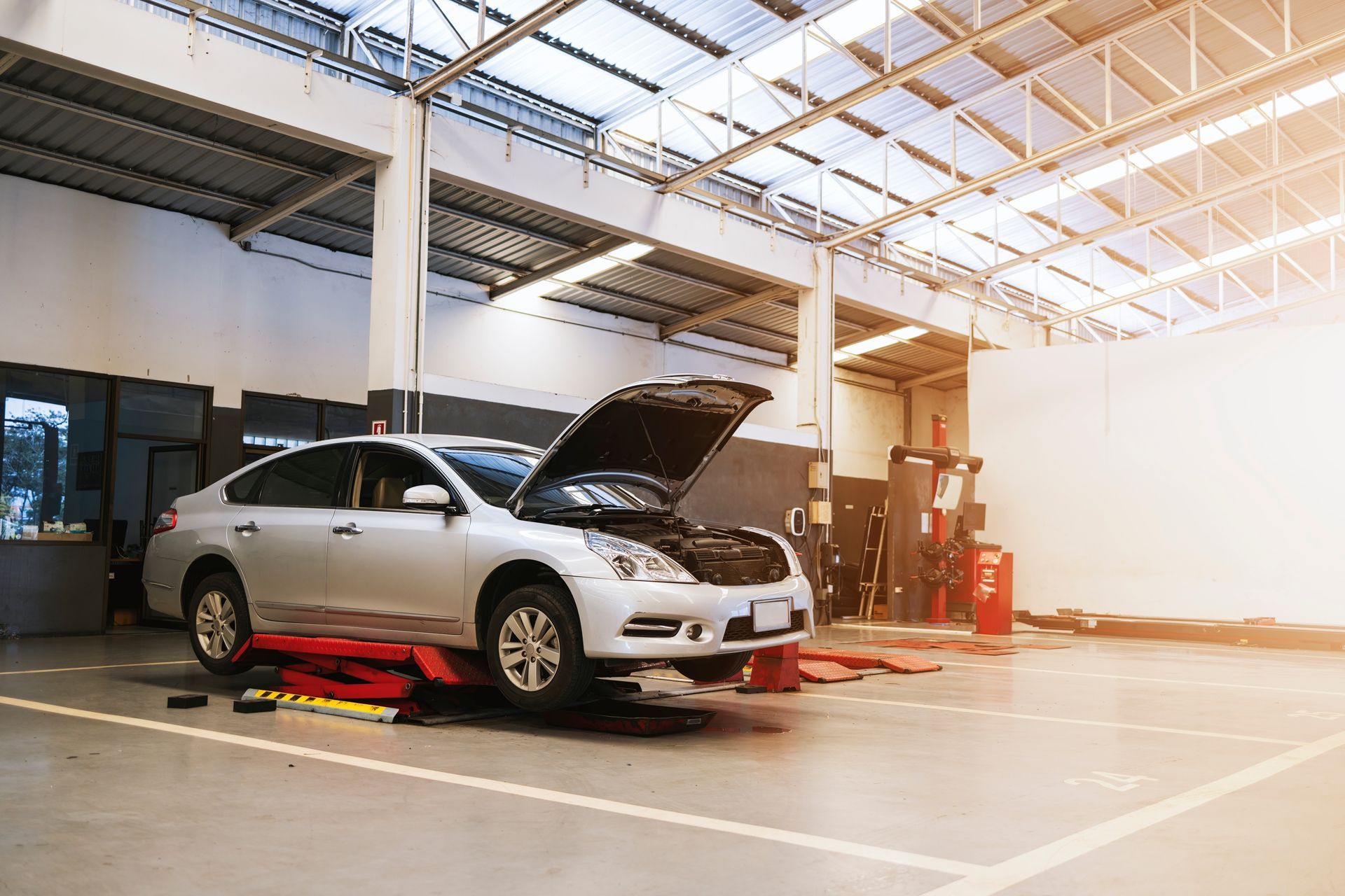 A Car is Sitting on a Lift in a Garage With Its Hood Open
