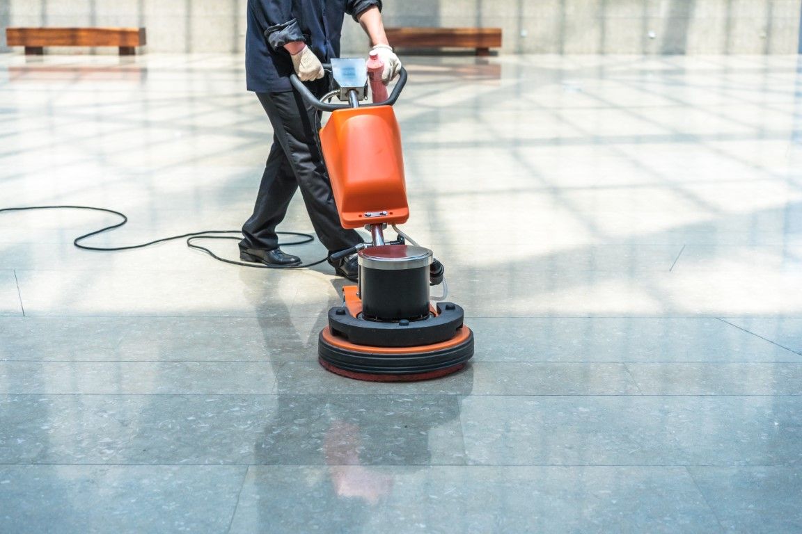 A man is cleaning a tiled floor with a machine.