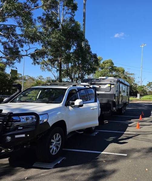A White SUV IS Parked Next To A Trailer In A Car Park — A Weigh In - Mobile Weighing Solutions in Noraville, NSW