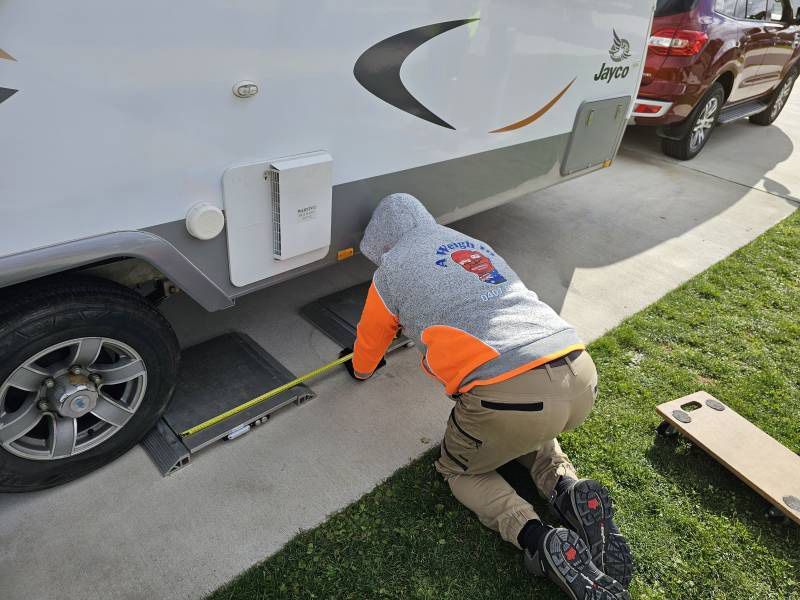 A Man Is Measuring A RV With A Tape Measure — A Weigh In - Mobile Weighing Solutions in Noraville, NSW