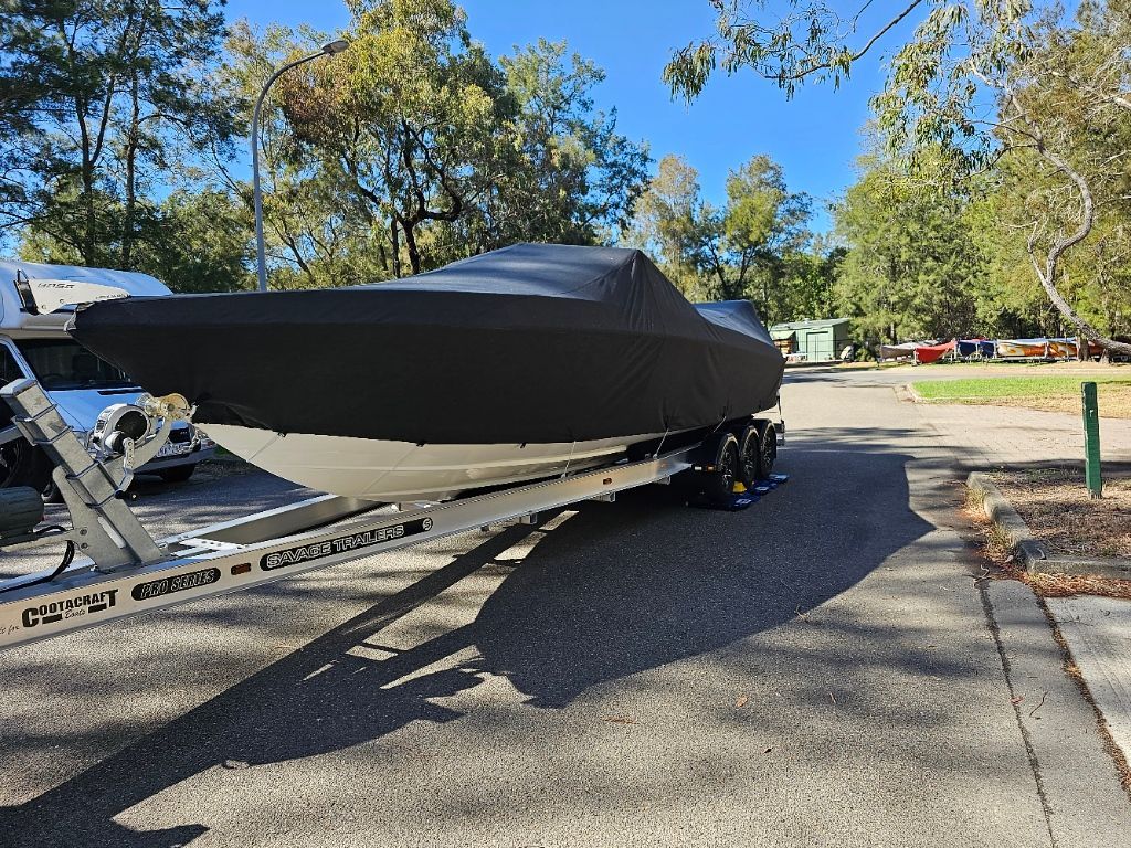 A White Boat Is Parked on A Blue Tarp in A Parking Lot — A Weigh In - Mobile Weighing Solutions in Noraville, NSW