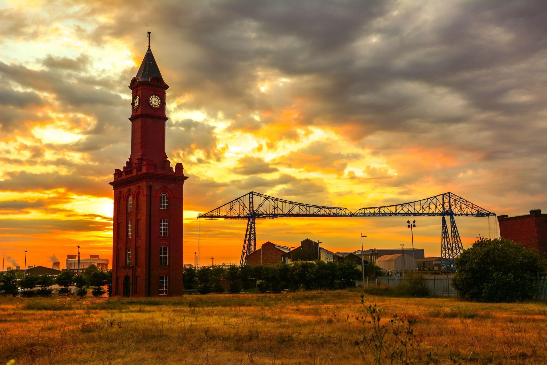 Teesside. Red brick clock tower and bridge silhouetted against a golden sunset.