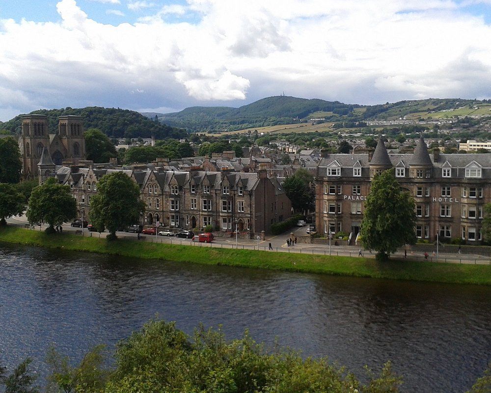 Inverness. Cityscape with river, buildings, hills, and cloudy sky.