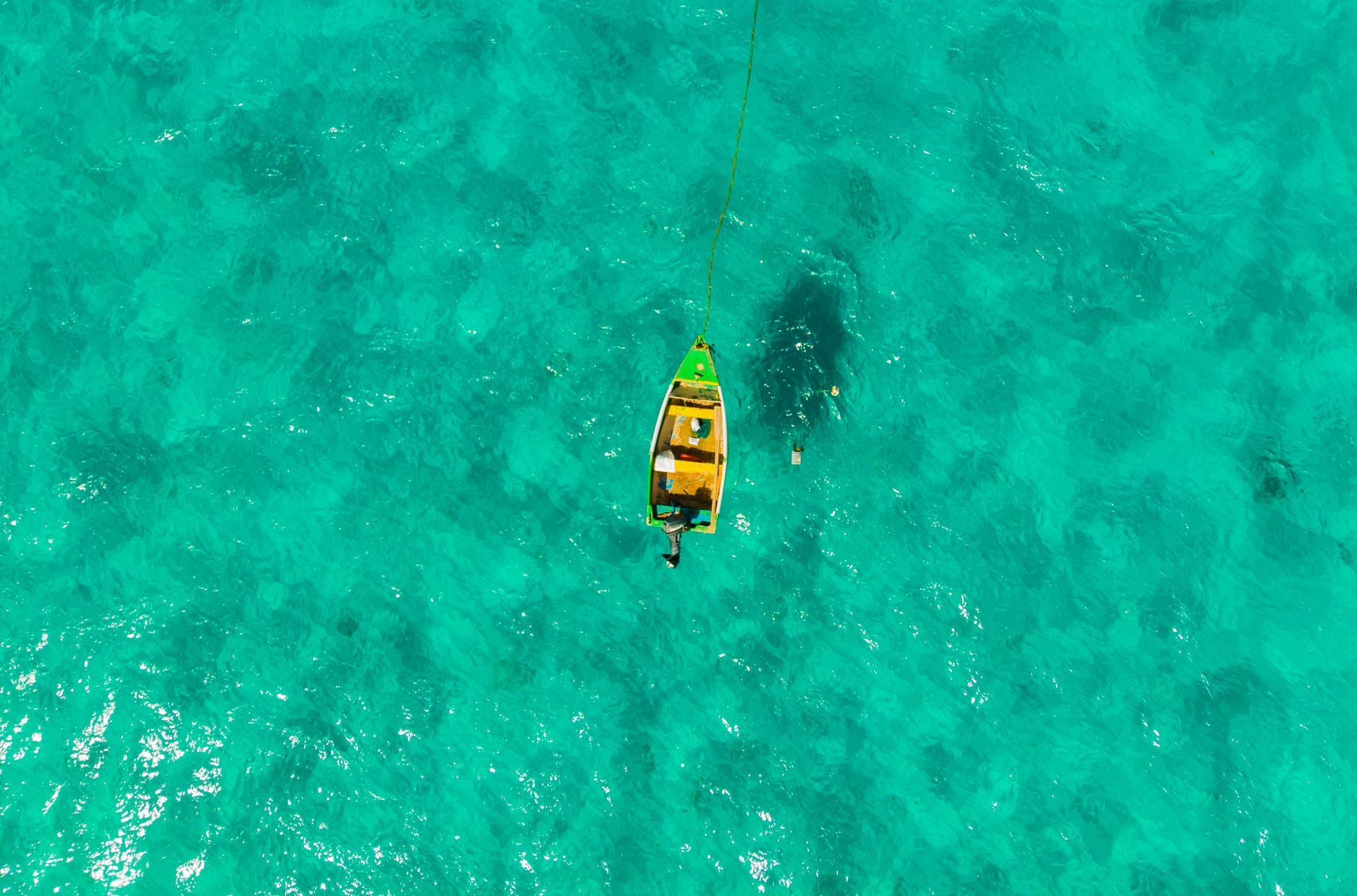 Small boat floats on turquoise water.