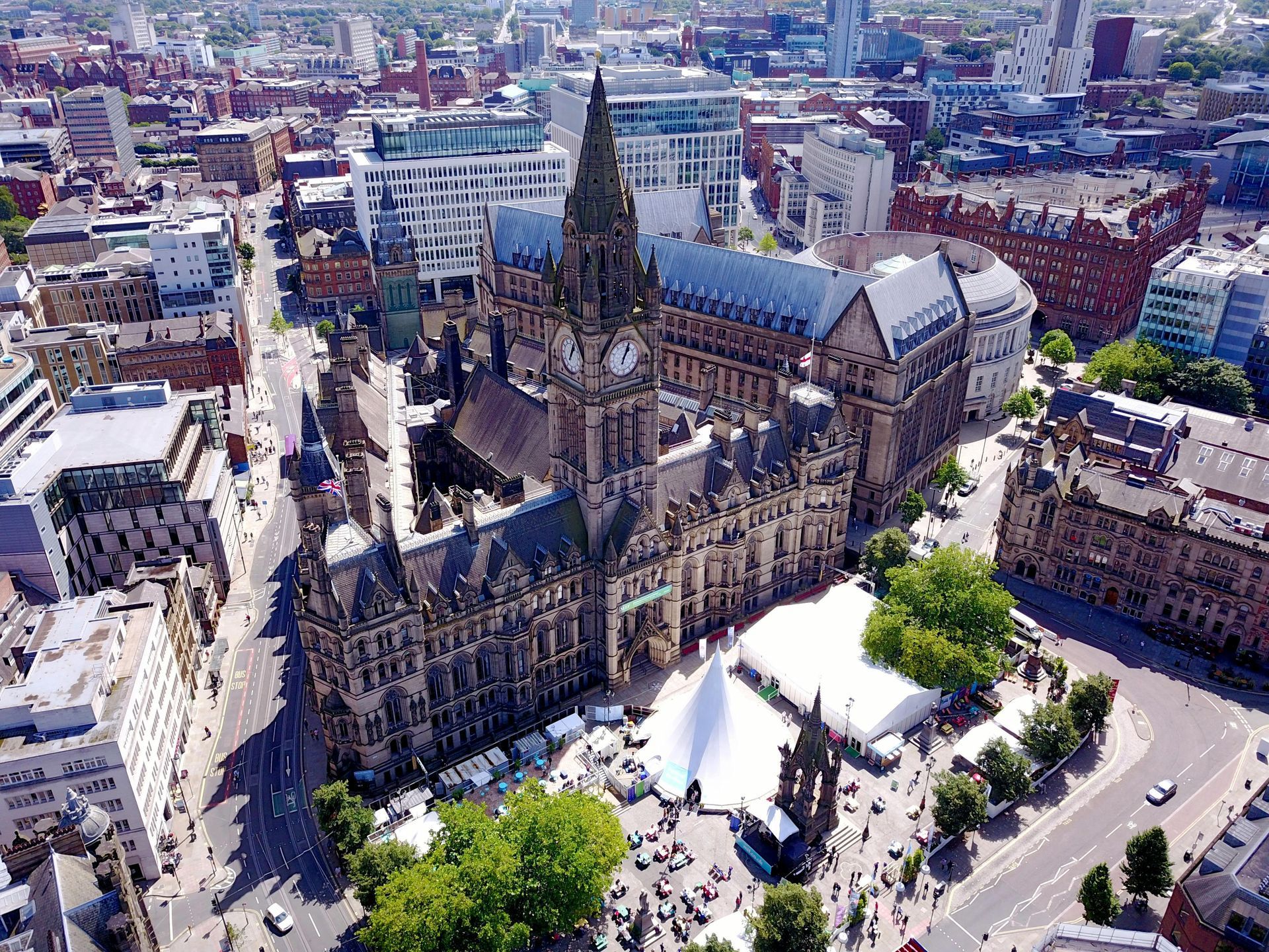 Aerial view of Manchester Town Hall with surrounding city buildings and a crowd.