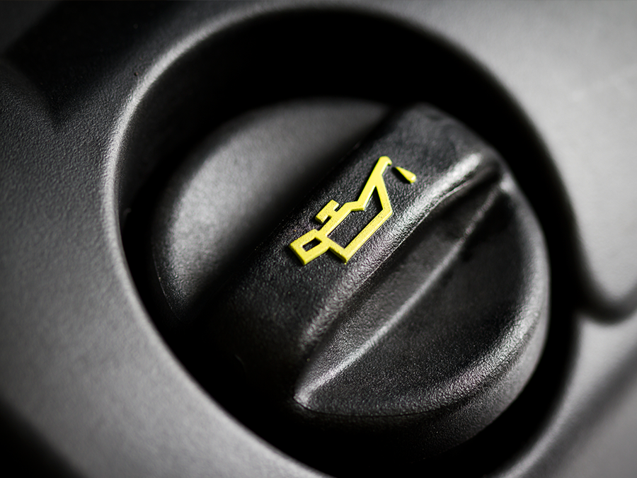 A close up of an oil cap on a car engine.