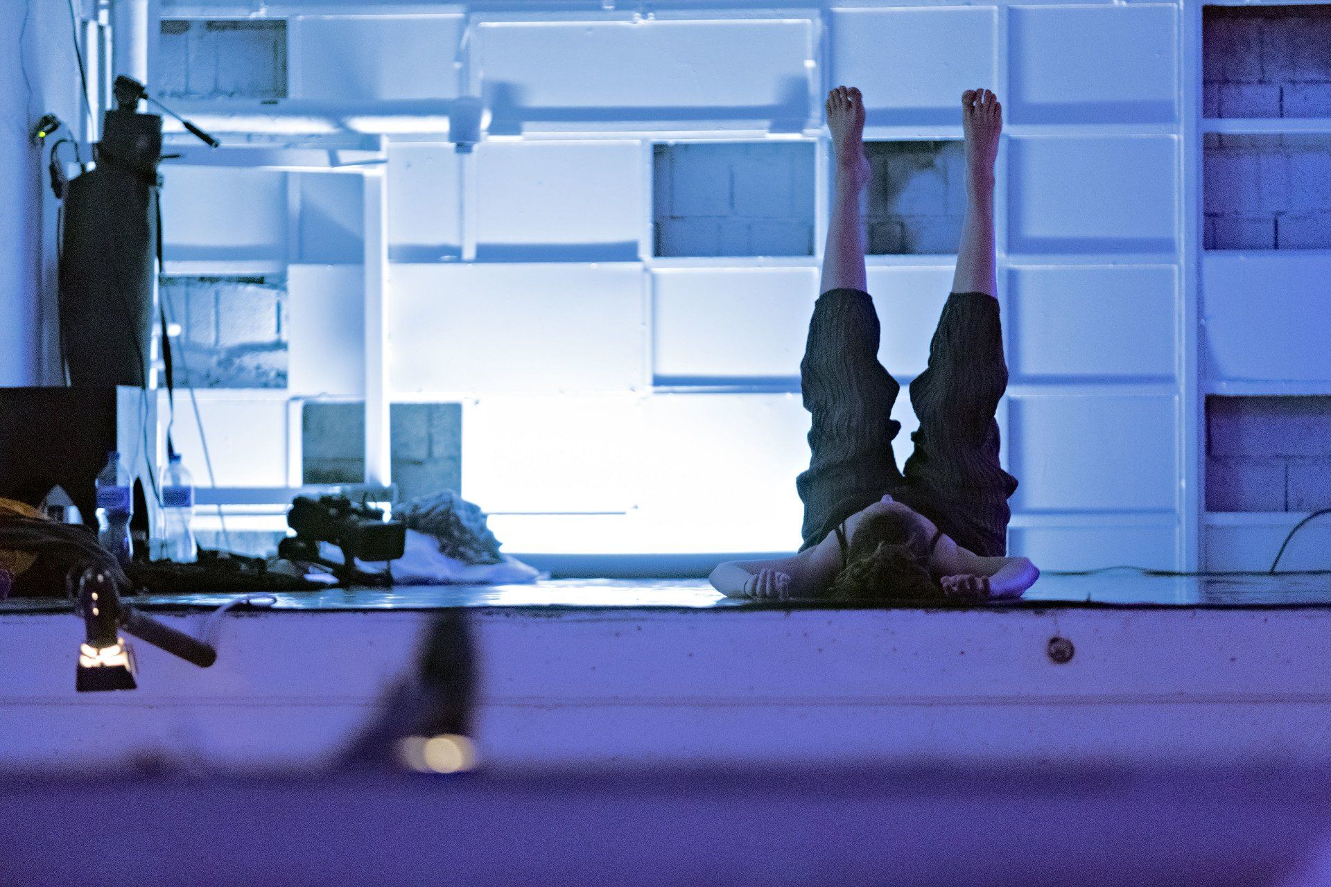 femme couchée sur le sol d'une pièce éclairée en bleu