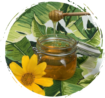 A jar of honey next to a yellow flower