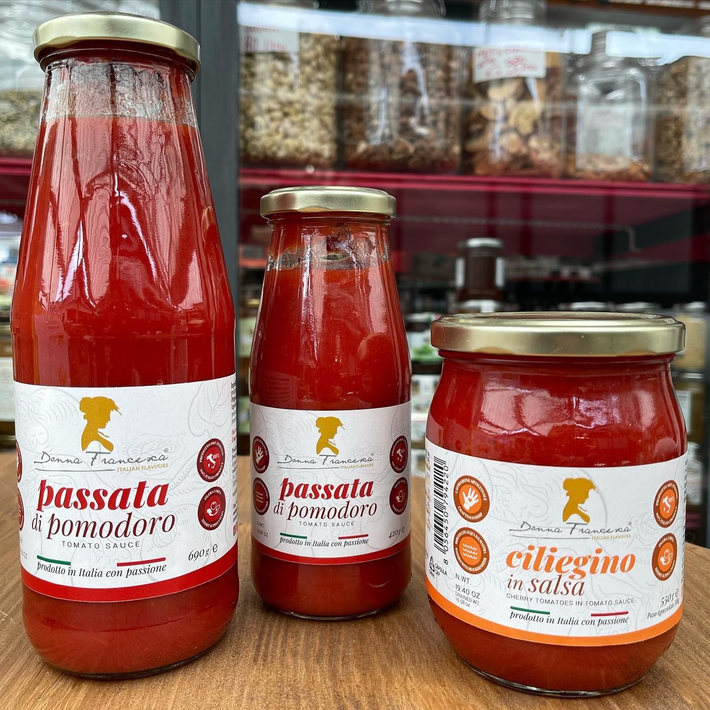 Tre barattoli di salsa di pomodoro sono appoggiati su un tavolo di legno.