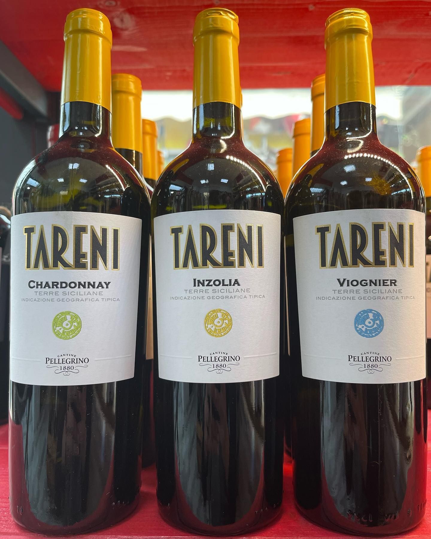 Tre bottiglie di vino tareni sono allineate su uno scaffale