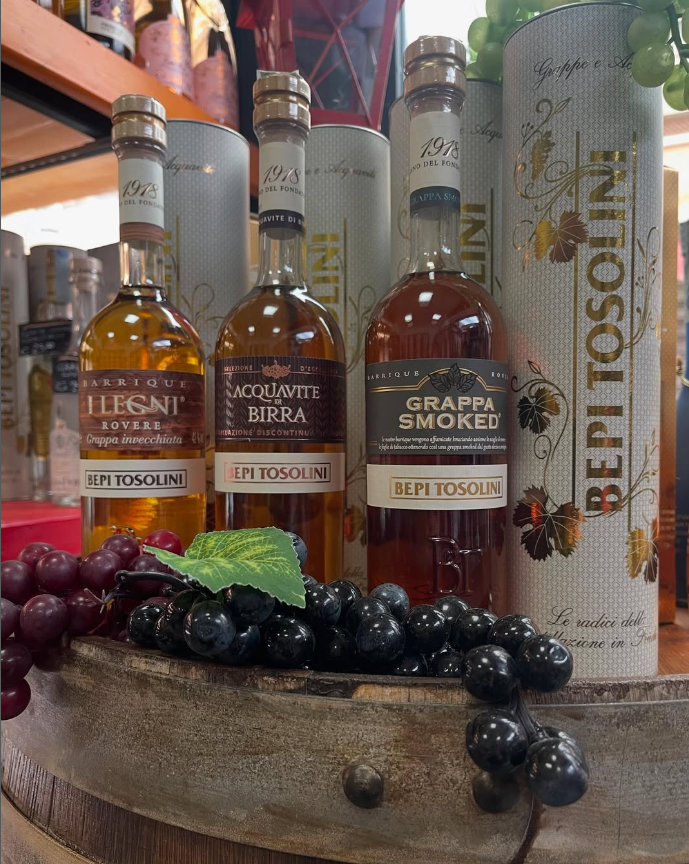 Un mucchio di bottiglie di vino sono appoggiate sopra una botte di legno.