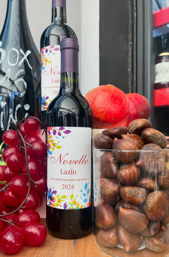 Una bottiglia di vino novello è appoggiata accanto a un bicchiere di castagne.