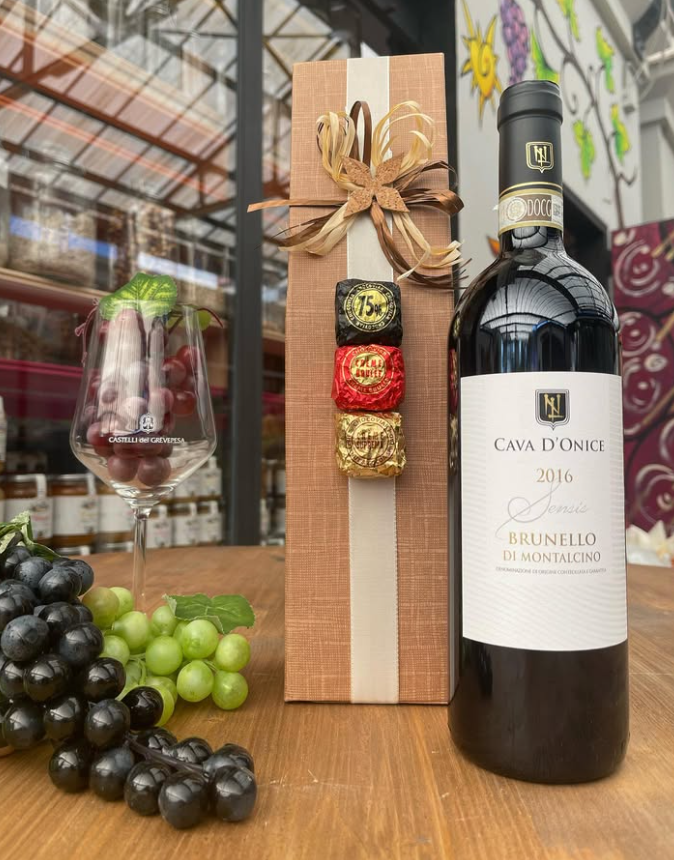 Una bottiglia di vino è appoggiata su un tavolo accanto a una scatola di cioccolatini.