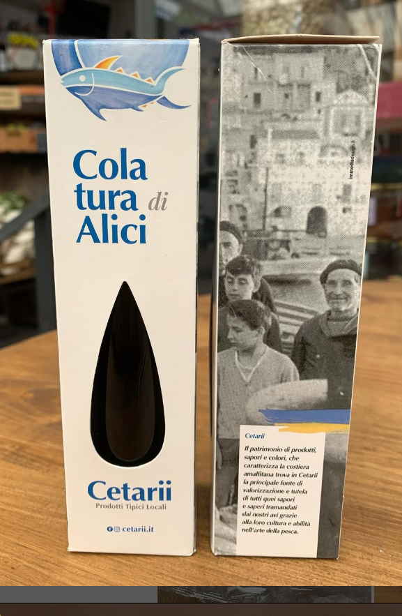 Una scatola di cola tura di alici è appoggiata su un tavolo di legno.