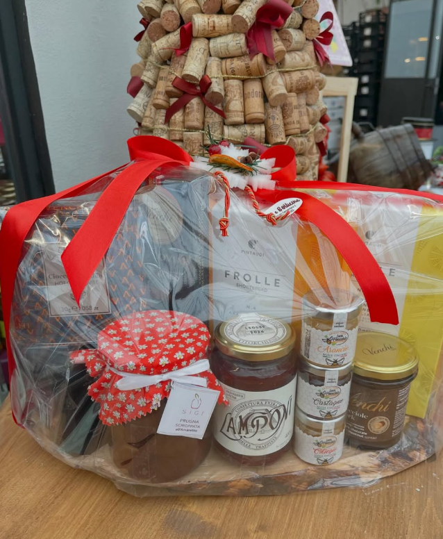 Un cesto pieno di barattoli di cibo e un albero di Natale fatto di tappi di sughero