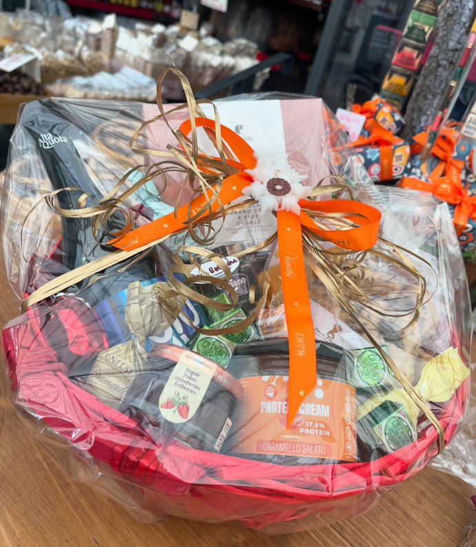 Un cestino rosso pieno di cibo e un nastro su un tavolo.