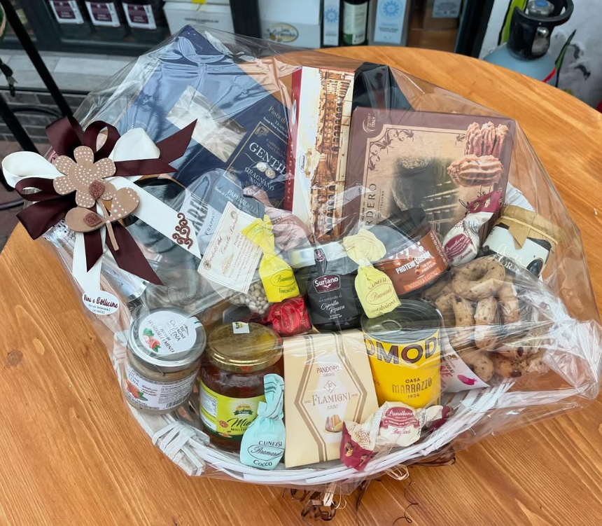 Un cesto pieno di cibo e bevande è appoggiato su un tavolo di legno.