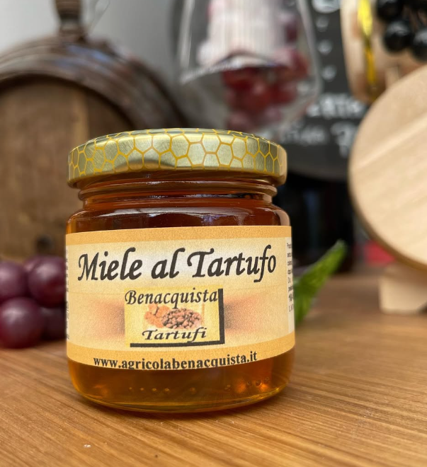 Un barattolo di miele al tartufo è appoggiato su un tavolo di legno