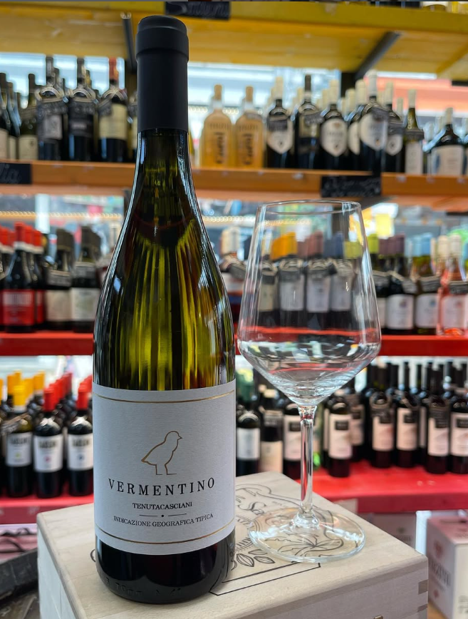 Una bottiglia di vino è appoggiata sopra una scatola accanto a un bicchiere di vino.