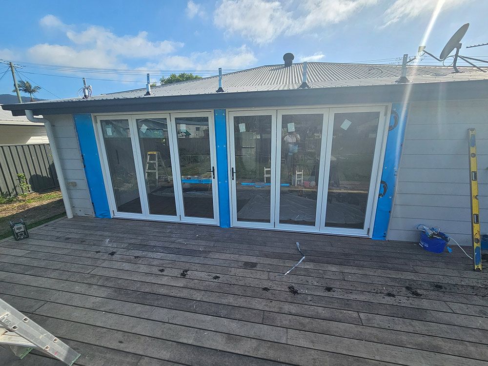 A House With Sliding Glass Doors And A Wooden Deck — Coffs Coast Building Pty Ltd in Toormina, NSW
